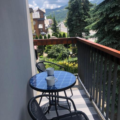 a table and chairs on a balcony with a view at Apartamenty Harnaś in Rytro