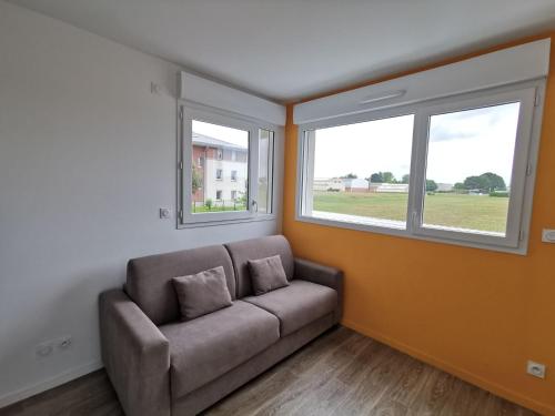 un salon avec un canapé et deux fenêtres dans l'établissement Studio St Malo cosy by Interhome, à Saint-Malo