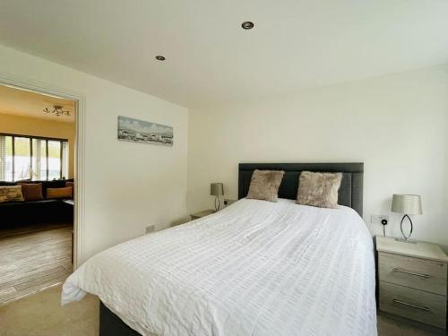 a bedroom with a white bed and a living room at Little Greenway Holiday Bungalow in Galmpton-on-the-Dart