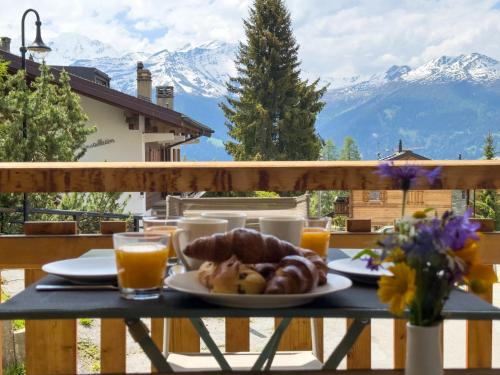 a table with a plate of food on a balcony with mountains at Apartment Stem 2 by Interhome in Verbier