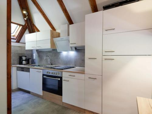 eine Küche mit weißen Schränken und einem Herd in der Unterkunft Holiday Home Am Sternberg 74 by Interhome in Frankenau