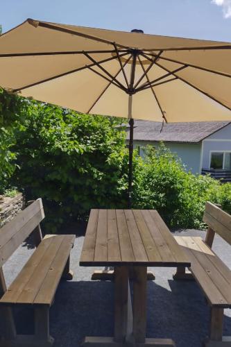 a picnic table with an umbrella and two benches at Apartment Meran-2 by Interhome in Görtschach