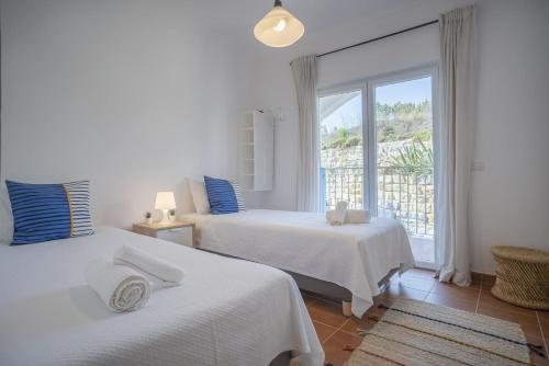 een witte slaapkamer met 2 bedden en een raam bij Beach & Nature Apartment - 2bedroom apt in Aljezur in Aljezur