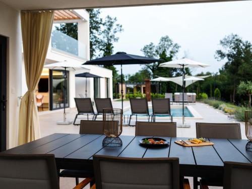 - une salle à manger avec une table, des chaises et des parasols dans l'établissement Holiday Home Villa Sonia by Interhome, à Nedeščina