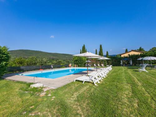 a swimming pool with white chairs and umbrellas at Holiday Home Lavanda by Interhome in Badia Agnano