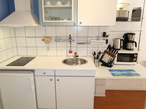 a kitchen with white cabinets and a sink at Apartment Tossens-6 by Interhome in Butjadingen OT Tossens