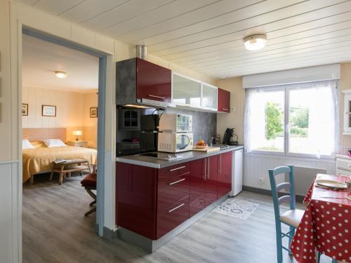uma cozinha com armários vermelhos e um quarto com uma cama em Holiday Home La Littorine by Interhome em Kersiroux