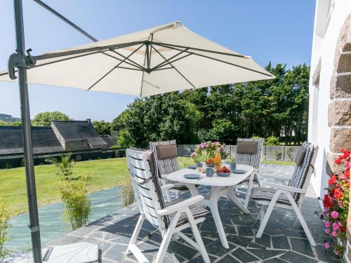 - une table et des chaises blanches sous un parasol sur la terrasse dans l'établissement Holiday Home Reve de Mer - LOQ215 by Interhome, à Locquirec