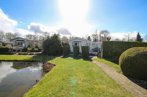 uma casa com um lago em frente a uma casa em Zonnig chalet aan mooie visvijver em Voorthuizen