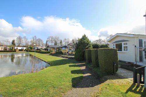 una casa con un estanque frente a una casa en Zonnig chalet aan mooie visvijver, en Voorthuizen