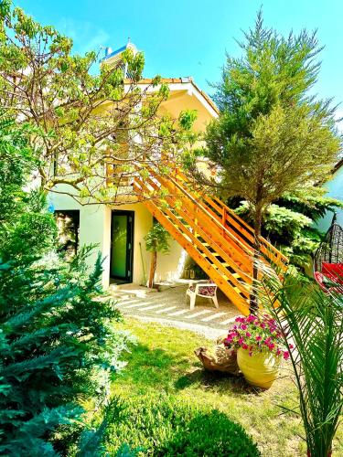 una casa amarilla con una escalera de madera en un patio en Saga en Mangalia