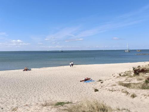 a beach with people laying on the sand and the water at Holiday Home Stavoren by Interhome in Stavoren