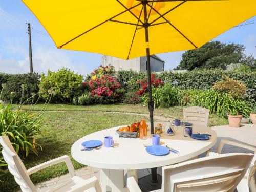 CléderにあるHoliday Home Ty Glaz - CED223 by Interhomeの白いテーブル(黄色い傘と椅子付)