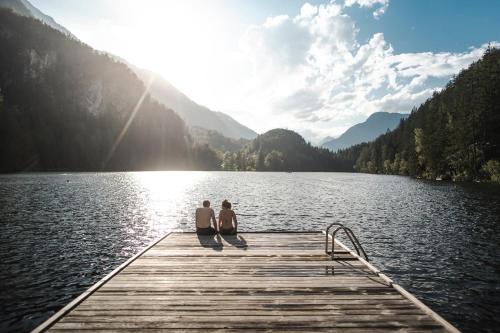 two people sitting on a dock on a lake at Mountain Moments in Sautens