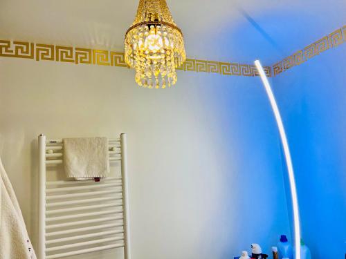 a bathroom with a chandelier and a blue wall at LES RÉSIDENCES DE DJIBRIL in Le Blanc-Mesnil