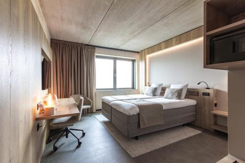 Nederweert的住宿－Hotel Rosveld，一间卧室配有一张床、一张书桌和一个窗户。
