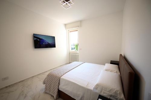 ein weißes Schlafzimmer mit einem Bett und einem TV an der Wand in der Unterkunft Dreamich - Delle Rive in Desenzano del Garda