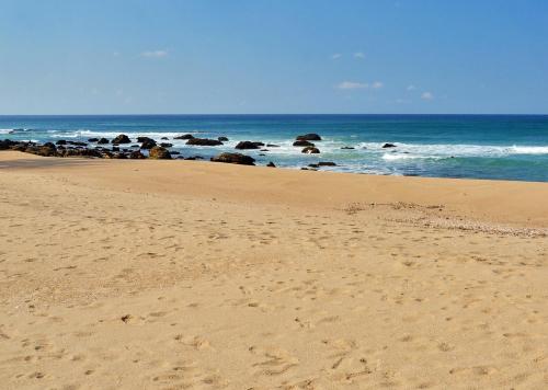 a sandy beach with rocks in the ocean at Bilene Lodge by Dream Resorts in Vila Praia Do Bilene
