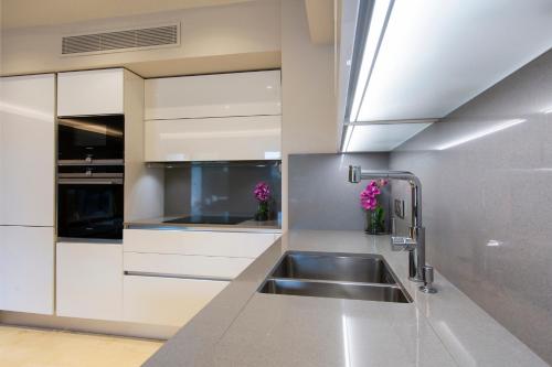 a kitchen with white cabinets and a stainless steel sink at Luxury garden apartment 2BR in the best development of Cap d'Antibes-Juan les Pins in Antibes