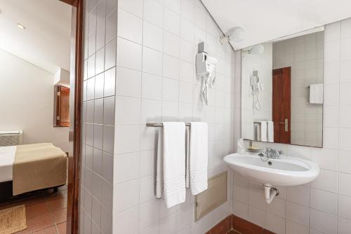 a white bathroom with a sink and a mirror at Alamal River Club in Gavião