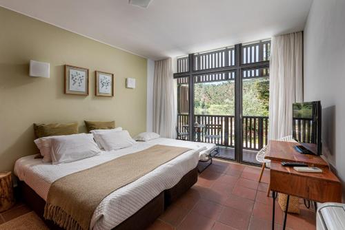 a bedroom with a large bed and a balcony at Alamal River Club in Gavião