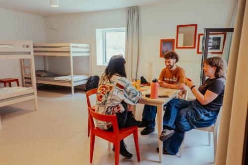 een groep mensen die aan een tafel in een kamer zitten bij Snuffel Youth Hostel in Brugge