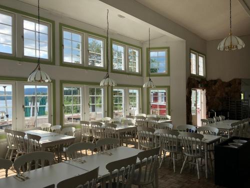 un comedor con mesas, sillas y ventanas en Skulesjön Hotell, en Bjästa