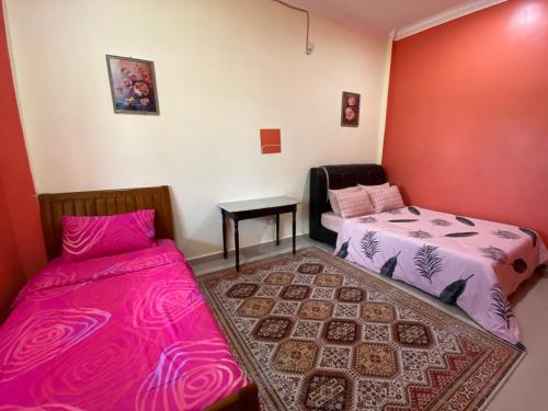 um quarto com duas camas e uma mesa com um tapete em MNOOR HOMESTAY em Marang