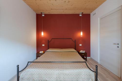 a bed in a room with a red wall at La Rosa Gialla Bio Apartments & rooms in Barolo