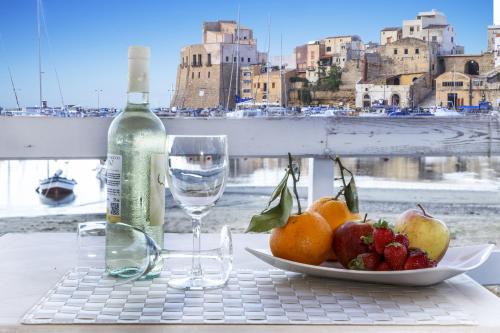 a table with a plate of fruit and a bottle of wine at Hotel Cala Marina in Castellammare del Golfo
