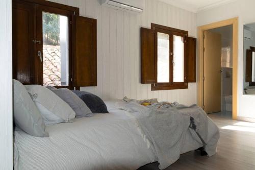 a bedroom with a bed with white sheets and windows at Precioso Estudio junto a la catedral in Burgos