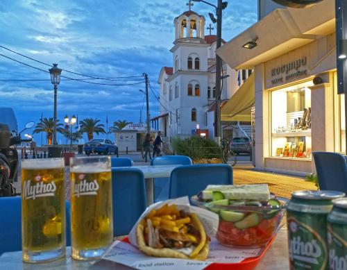 a table with a plate of food and two glasses of beer at Vila Europe R in Paralia Katerinis