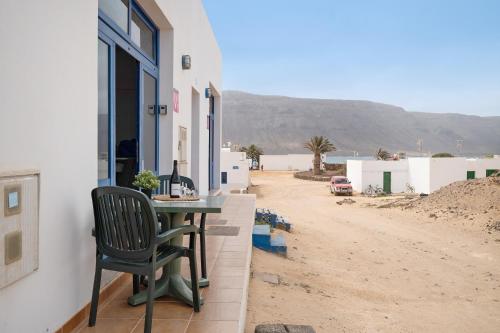 a table and a chair sitting on the side of a house at Apartamento Callao, La Graciosa in Caleta de Sebo
