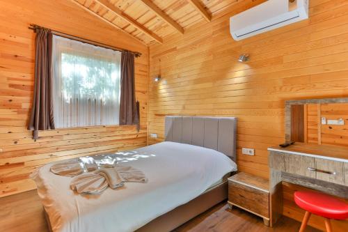 a bedroom with a bed in a wooden cabin at Cinderella Pension & Bungalow in Cıralı