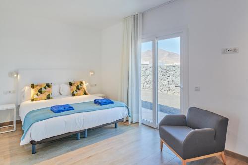 a bedroom with a bed and a chair and a window at Blancazul Villa Tajame 2 in Playa Blanca