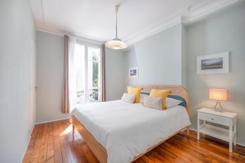 una camera da letto con un grande letto bianco con cuscini gialli di Bastille Trousseau Apartment a Parigi
