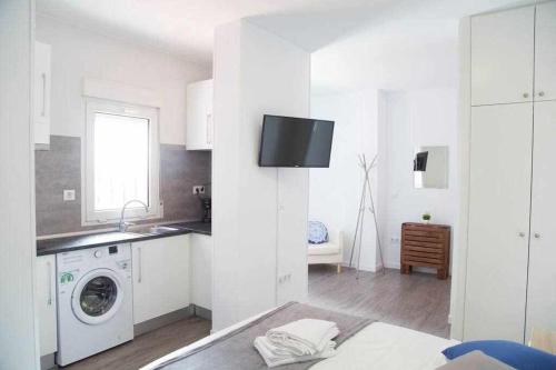 Biała kuchnia z pralką i zlewem w obiekcie Comodo y agradable estudio en Madrid centro A6 w Madrycie