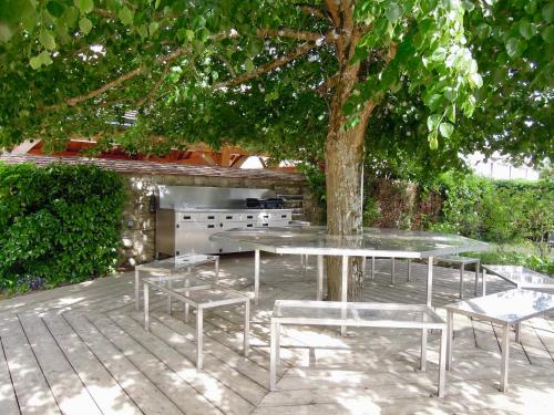 eine Terrasse mit einem Tisch und Stühlen unter einem Baum in der Unterkunft Le Cottage des 3 Pignons in Noisy-sur-École