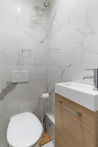 une salle de bain blanche avec des toilettes et un lavabo dans l'établissement Grands Boulevards 22 : Appartement Cosy 1BR-4P, à Paris
