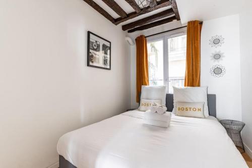 une chambre avec un lit blanc et une fenêtre dans l'établissement Grands Boulevards 22 : Appartement Cosy 1BR-4P, à Paris