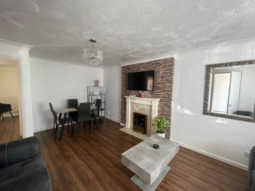 a living room with a fireplace and a table at Corby Guest House in Corby