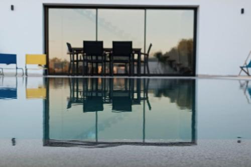 dos sillas están sentadas en el reflejo del agua en Splendide maison de campagne avec piscine et vue panoramique., en El Maamoura