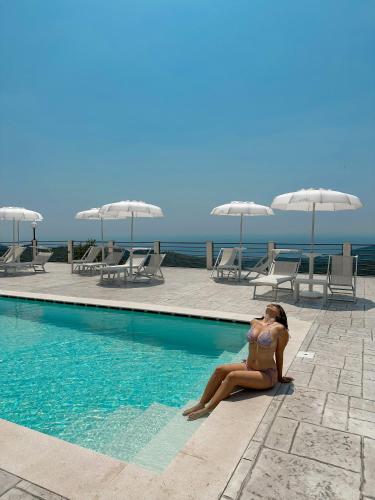 a woman in a bikini sitting next to a swimming pool at Tenuta Vallina - Golfo di Policastro in Tortorella