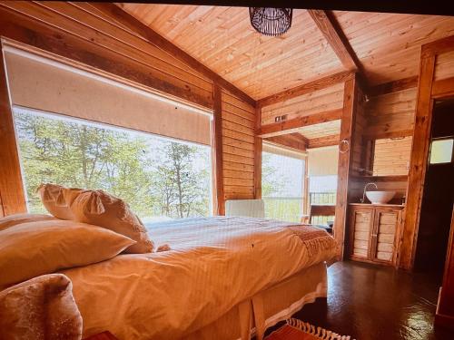 a bedroom with a large window in a log cabin at Calafate lodge patagonia in Coihaique