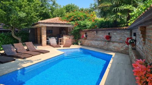 a swimming pool in a yard with chairs and a house at Villa Amalia Apartment 2 in Malinska