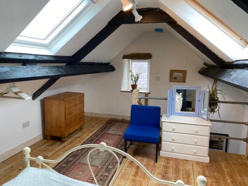 a attic room with a blue chair and a mirror at The Soap Barn in Manorbier