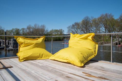 twee gele kussens op een steiger naast het water bij Besonderer Urlaub auf Hausboot TYSTNADEN in Hamburg