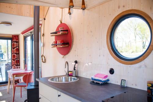 una pequeña cocina con fregadero y ventana en Besonderer Urlaub auf Hausboot TYSTNADEN en Hamburgo