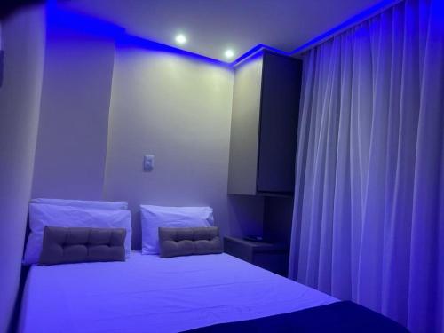 a bedroom with a large bed with purple lighting at Farol Barra Flat maravilhoso 2 quartos Barra Salvador in Salvador