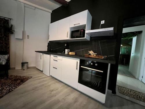 une cuisine avec des armoires blanches et un four à plaques de cuisson dans l'établissement la savane room, à Montagnac